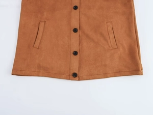 Detail of caramel suede jacket texture featuring black buttons and symmetrical side pockets