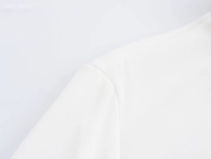 Dettaglio ravvicinato delle cuciture sulla spalla di una camicia bianca a maniche lunghe