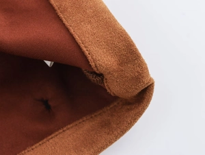 Detailed close-up of brown suede fabric and knit material stitching on high-quality jacket