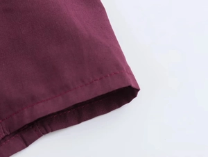 Detailed macro view of the single-needle hem stitching on a deep red woven shirt