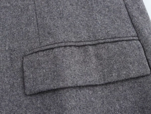 Close-up of deep gray wool blend suit jacket showing flap pocket detail and neat stitching