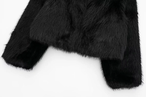 Close-up detail of plush black faux fur coat showing soft texture on hem and sleeves