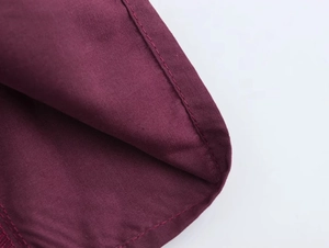 Macro shot of precise stitching and fine texture on burgundy raglan sleeve fabric