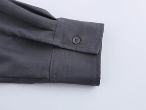 Dettaglio del polsino della camicia grigio scuro con cuciture e bottone di qualità