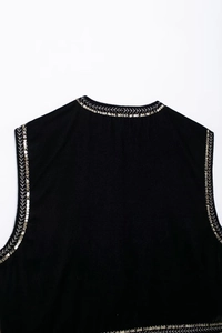 Dettaglio del ricamo di piume dorate e argentate su un gilet di velluto nero elegante