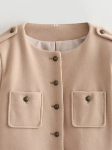 Detailed close-up of a beige wool jacket featuring vintage metal buttons and pocket details