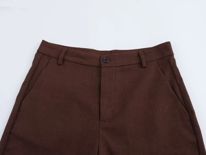 Dettagli dei pantaloni marrone scuro con chiusura a bottone e trama del tessuto di alta qualità