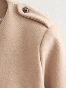Close-up of vintage metallic button and epaulette detail on khaki wool blend coat