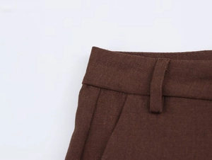 Dettaglio dei passanti e delle cuciture in vita sui pantaloni marroni in tessuto