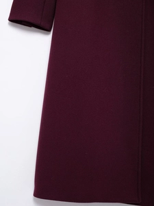 Detailed close-up of dark burgundy wool blend fabric and side stitching on this coat