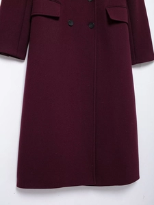 Close-up of double-breasted wine red wool coat featuring flap pockets and woven texture