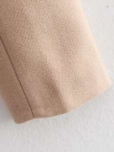 Detailed macro view of camel wool blend fabric texture and stitching on the sleeve cuff