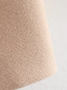 Detailed close-up of beige wool felt fabric texture with soft fiber finish for winter coats