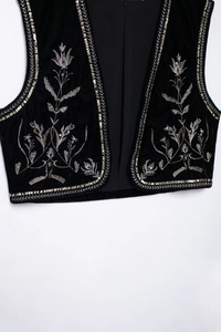 Dettaglio del gilet in velluto nero con intricati ricami floreali e paillettes metalliche