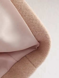 Close-up of light pink fuzzy wool fabric texture and smooth lining of the fashion coat
