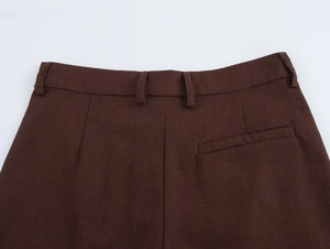 Dettaglio dei pantaloni marroni a vita alta con texture del tessuto e tasca posteriore