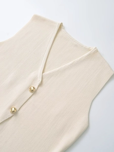Détail du gilet en maille crème avec col en V et boutons métalliques dorés