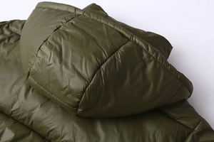 Detail shot of olive green hooded quilted jacket featuring horizontal padded stitching