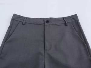 Dettaglio ravvicinato della vita dei pantaloni grigi con bottone e patta con zip