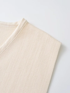 Gros plan sur le col en V et la texture en maille fine du gilet sans manches beige