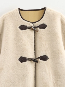 Detail of faux fur coat featuring cream lamb wool texture and dark brown toggle closures