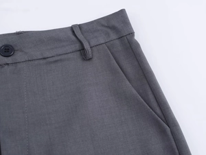 Dettaglio dei pantaloni a vita alta grigio scuro con chiusura a bottone e tasche