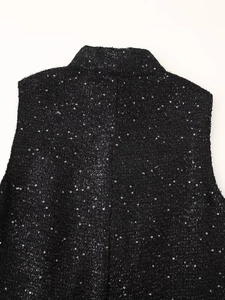 Détail du gilet en tweed noir à paillettes montrant le col montant et le tissu brillant