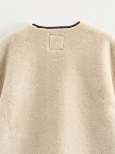 Detailed close-up of cream faux fur collar with refined dark piping and stitching