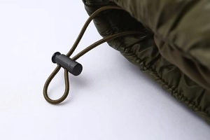 Detailed macro view of olive green quilted jacket featuring an elastic drawstring and toggle