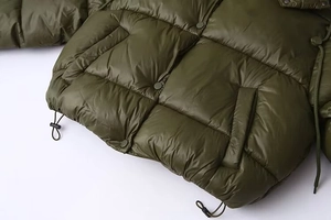 Detail of army green puffer jacket featuring quilted hem and adjustable drawstring closure