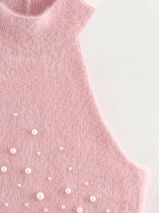 Dettaglio del tessuto a maglia rosa con texture soffice e decorazioni di perle