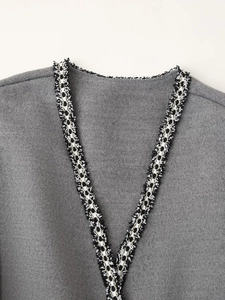 Detail of V-neckline with decorative black and gold braided trim on a grey wool coat