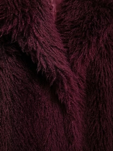 Detailaufnahme der flauschigen burgunderroten Kunstpelz-Textur dieses Wintermantels