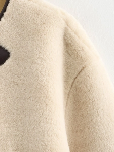 Detail of faux fur coat featuring high-quality beige plush texture and dark brown trim
