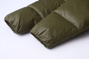 Detail of elastic cuffs and quilted texture on olive green hooded puffer jacket for women