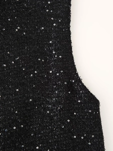 Détail du tissu en tweed noir avec paillettes argentées et texture tissée sur la robe