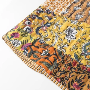 Detailed macro view of quilted floral vest with vibrant orange patterns and striped piping