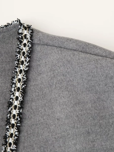 Detail of grey wool blend coat featuring elegant black, white, and gold woven braid trim
