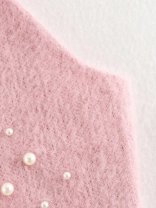 Dettaglio del tessuto a maglia rosa peluche con perle bianche e morbida trama in mohair
