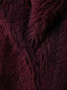 Makro-Detail der burgunderroten Kunstpelz-Textur des langen Wintermantels aus Webpelz