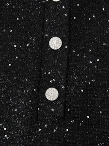 Détail du tissu en tweed noir à paillettes avec deux boutons ornés de strass brillants