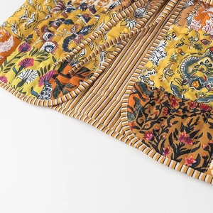 Detailed close-up of quilted floral patchwork pattern and stitching on a warm-toned vest