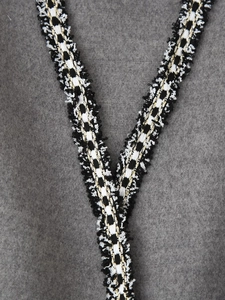 Detail of grey wool coat featuring chic black and gold braided trim with fringe