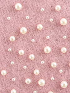 Dettaglio di maglia rosa in finto visone con decorazioni di perle bianche sparse