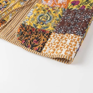 Close-up of bohemian patchwork quilted vest with vibrant floral patterns and vertical stitching