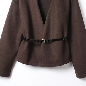 Close-up of brown knit cardigan with a black faux crocodile leather belt and silver buckle