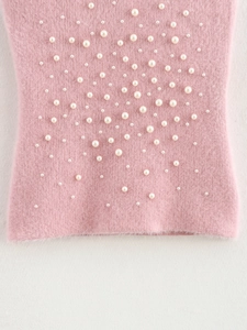 Dettaglio del tessuto in maglia rosa pelosa con eleganti decorazioni di perle artificiali