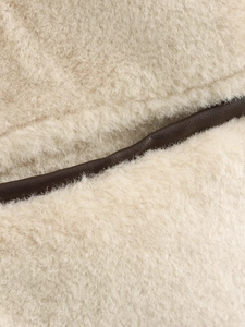 Detailed close-up of faux fur texture with contrast dark brown leather piping and stitching