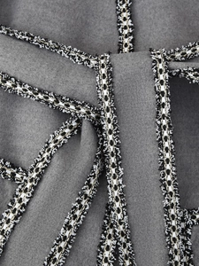 Close-up of classic black and white tweed trim on a grey woven fabric coat