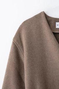 Close-up of premium brown wool coat shoulder with fine stitching and origin label